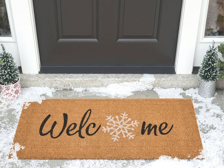 Fasssauna aus Holz mit Schindeldach und Schornstein auf einer Holzterrasse im Garten bei Dämmerung.
