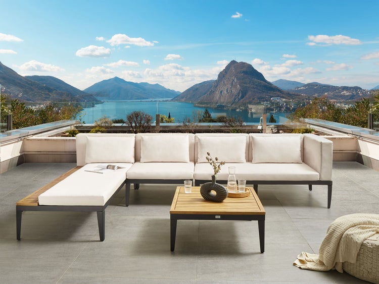 Gartenlounge-Set mit Tisch und Bergpanorama im Hintergrund.
