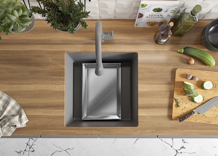 Küchenszene mit Spüle, Armatur, Schneidebrett mit Zucchini und Kochbuch