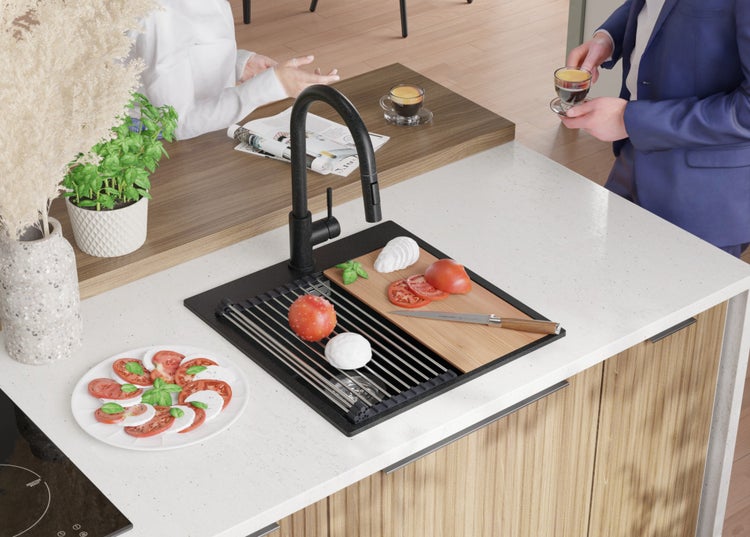 Küchenszene mit Spüle, Armatur, Schneidebrett, Tomaten, Mozzarella und einem Teller mit Caprese