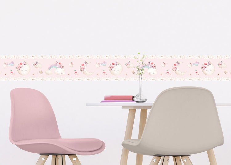 Selbstklebende Tapetenbordüre für das Kinderzimmer mit Motiven von schlafenden Monden, Regenbögen und Sternen an einer Wand über einem Tisch.