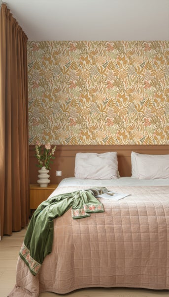 Schlafzimmer mit floraler Tapete, Bett mit Tagesdecke und Vorhängen