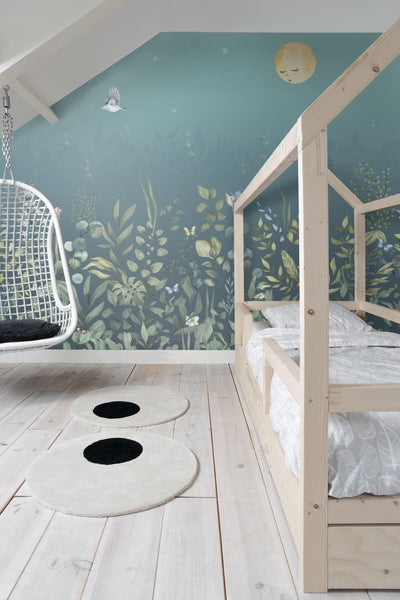 Kinderzimmer mit Holzbett, Hängesessel und Wandtapete mit Pflanzenmotiven