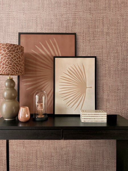 Dekoratives Wohnambiente mit Kommode, Tischleuchte und Wandbildern mit Palmenmotiven vor gemusterter Tapete.
