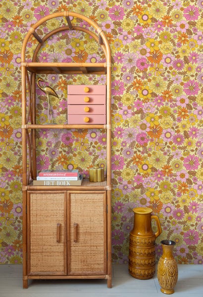 Retro-inspirierte Szene mit Blumenmustertapete und Regalsystem aus Rattan.