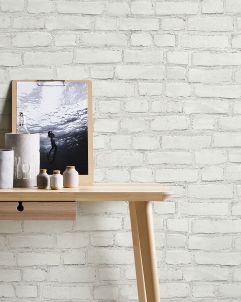 Heller Schreibtisch mit Dekoration vor einer Ziegelwand