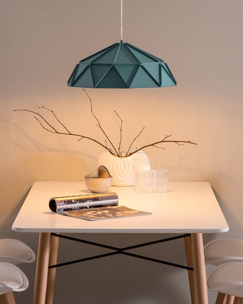 Szene mit einem Esstisch, dekoriert mit einer Vase, Geschirr und einer geometrischen Pendelleuchte.