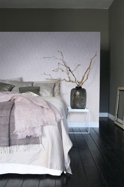 Schlafzimmer mit Bett, Tapete und Beistelltisch mit Dekoration