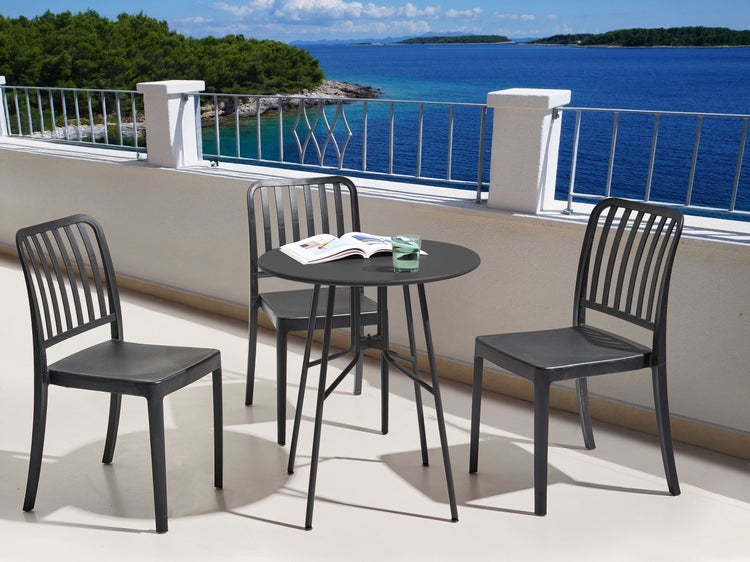 Gartentischgruppe mit drei Stühlen auf einer Terrasse mit Meerblick