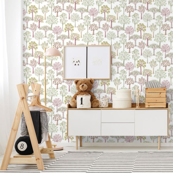Kindertapete mit Baum-Motiv in einem hellen Kinderzimmer mit weißem Sideboard, Kleiderständer aus Holz und gestreiftem Teppich.