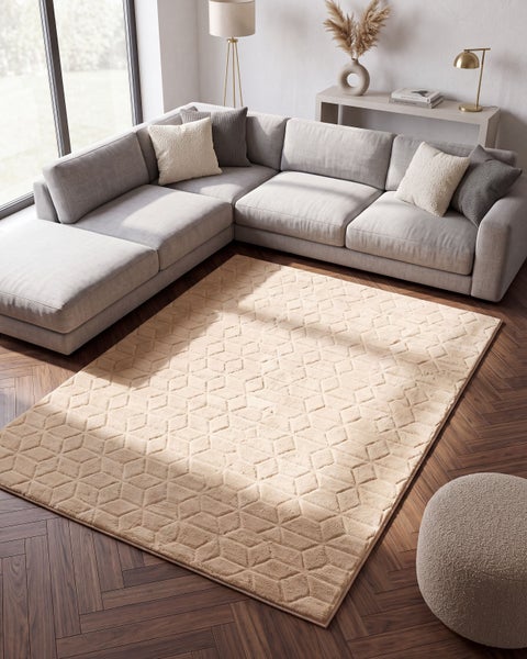 Wohnzimmer mit Ecksofa und einem beigen Teppich mit geometrischem Muster auf einem Parkettboden in einem modern eingerichteten Raum.
