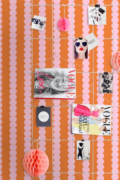 Dekoratives Wandgitter mit Fotos, Magazinen und Papierdekorationen an Haken und Klammern