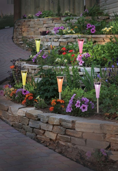 Gartenszene mit dekorativer Gartenbeleuchtung in Blumenbeeten auf verschiedenen Ebenen