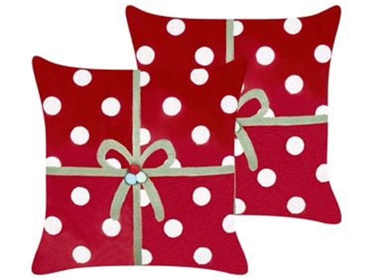 Zwei quadratische Dekokissen mit Punktemuster und einer Applikation in Form einer Geschenkverpackung mit Schleife für die Weihnachtsdekoration