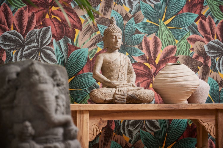 Dekoratives Interieur mit Frau, Buddha-Kopf, Statue und gemusterter Tapete mit Pflanzenmotiven