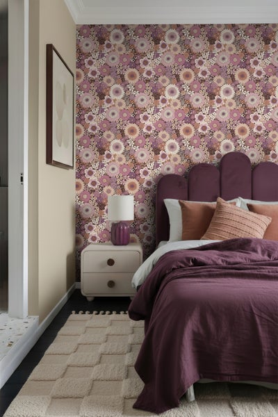 Schlafzimmer mit geblümter Tapete, Bett, Nachttisch, Lampe und Teppich