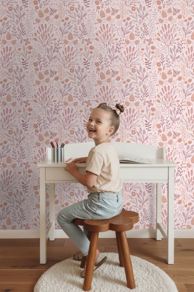 Mädchen sitzt an einem Schreibtisch vor einer floralen Tapete