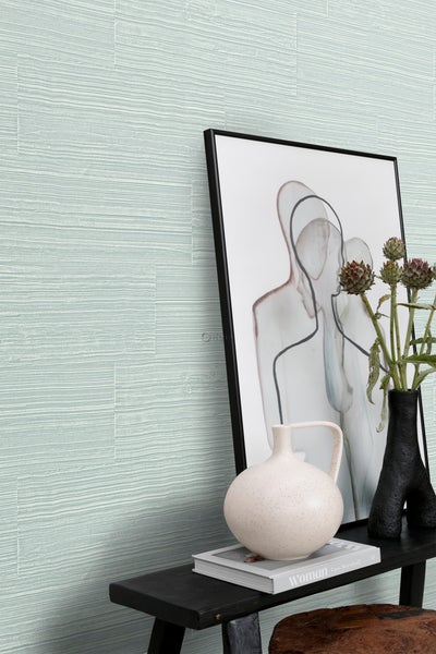 Innenraum mit Wandpaneelen, dekoriert mit einer Skulptur, einer Vase und einem gerahmten Bild auf einem Tisch.