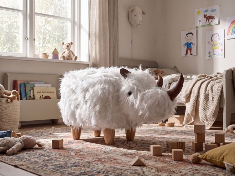 Ein Kinderhocker in Nashornoptik mit flauschigem Bezug und Holzbeinen steht in einem hellen, eingerichteten Kinderzimmer.