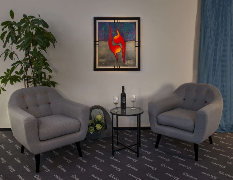 Wohnzimmer mit zwei Sesseln, einem Tisch mit Wein und Gläsern sowie einem gerahmten Bild an der Wand