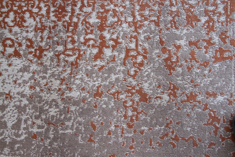 Nahaufnahme eines Teppichs mit abstraktem Vintage-Muster in Terrakotta und Grau.