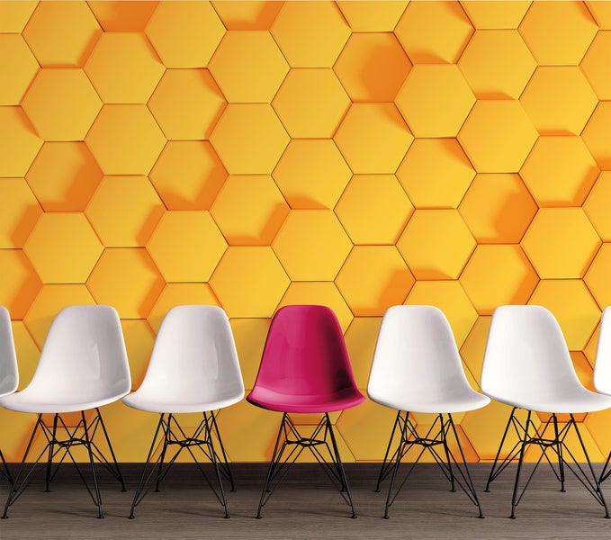 Modernes Interieur mit einer Reihe von Schalenstühlen vor einer gelben 3D-Wandgestaltung mit hexagonalem Wabenmuster.