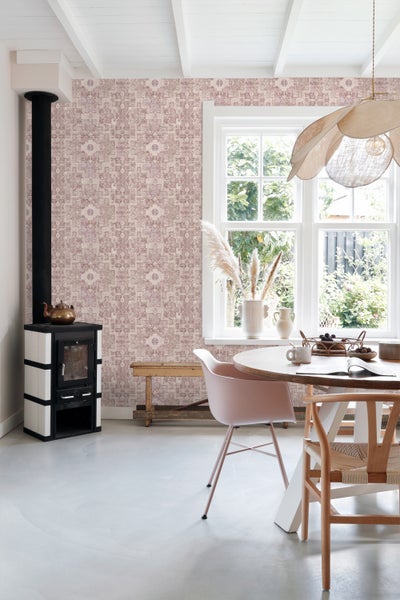 Zimmergestaltung mit gemusterter Tapete, zwei Hüten an der Wand, einem Hocker und glitzernden Stiefeln.