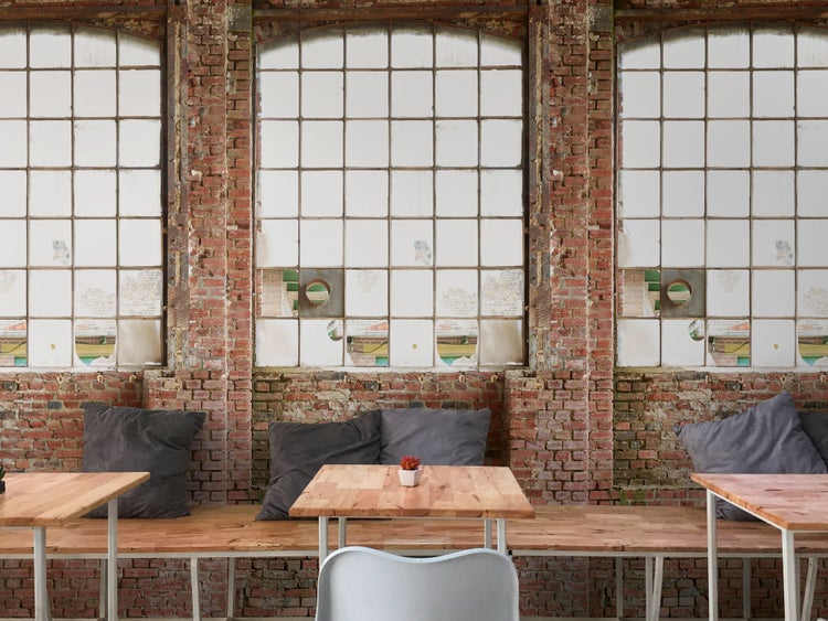 Raum mit Tischen, Bänken und Sichtmauerwerk