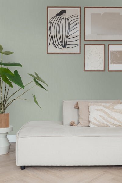 Heller Wohnraum mit Sofa, Pflanzen und Wandbildern für eine freundliche Atmosphäre.