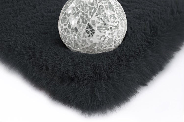 Schwarzer Kunstfell-Teppich mit weicher Oberfläche und dekorativer Mosaikkugel.