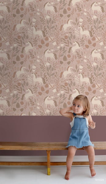 Mädchen vor einer Kinderzimmerwand mit Einhornmuster und braunem Sockel