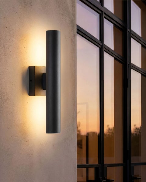 Moderne schwarze Außenwandleuchte in Zylinderform mit Up-and-Down-Effekt an einer Hauswand.