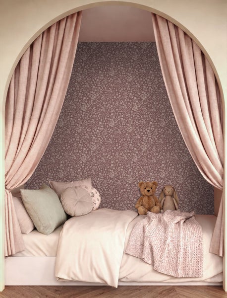 Gemütliche Kinderbett-Nische mit floraler Vliestapete, eingerahmt von einem Rundbogen und Vorhängen, inklusive Kissen und Kuscheltieren.