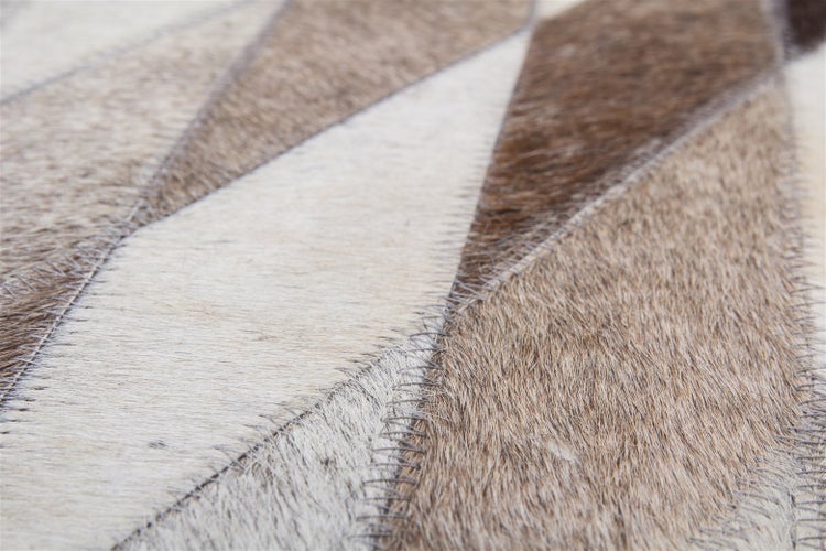 Nahaufnahme eines Patchwork-Teppichs aus Kuhfellstücken mit sichtbarer Zickzack-Naht.