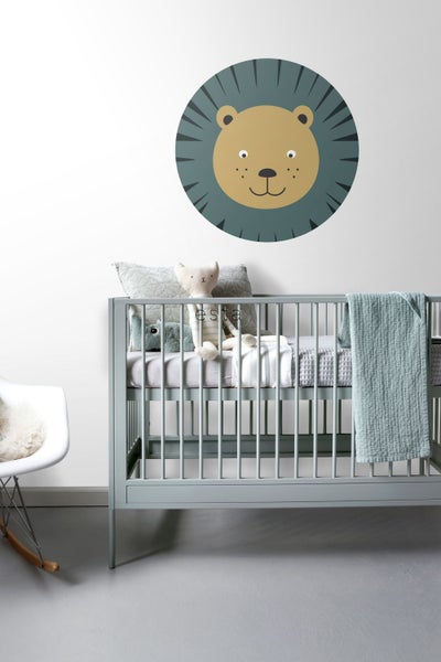 Kinderzimmer mit Gitterbett, Dekokissen, Kuscheltieren und Wandsticker Löwe