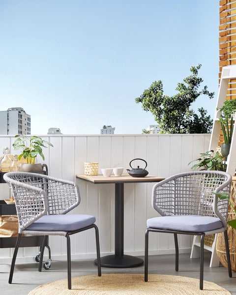 Balkonszene mit zwei Sesseln, Tisch, Teekanne und Pflanzen für eine entspannte Atmosphäre
