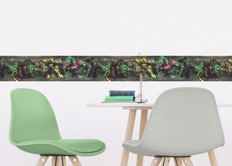 Tapetenbordüre mit Transformers-Motiven an einer Wand in einem hellen Zimmer mit Tisch und Stühlen.