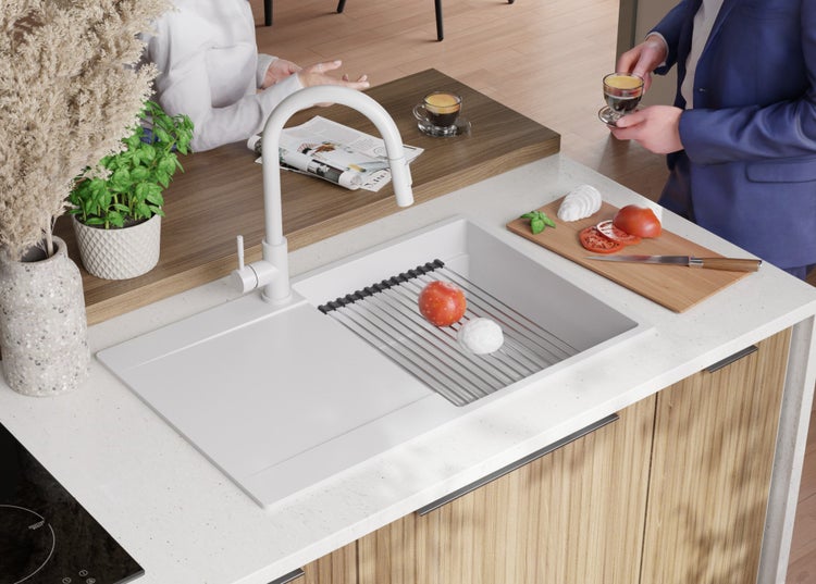 Küchenspüle mit Abtropfgestell, Armatur, Schneidebrett mit Mozzarella und Tomaten auf einer Küchenarbeitsplatte.
