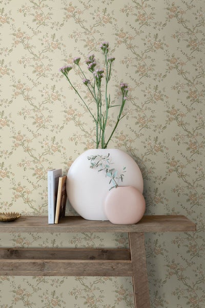 Vliestapete mit floralem Vintage-Muster aus Rosen und Ranken hinter einem Holztisch mit Vasen und Büchern.