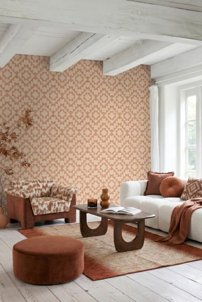 Wohnzimmer mit Tapete in geometrischem Rautenmuster, Sofa, Sessel, Couchtisch aus Holz und Teppich.