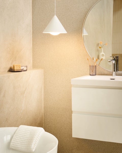 Modernes Badezimmer mit Waschbeckenunterschrank, rundem Spiegel und Pendelleuchte