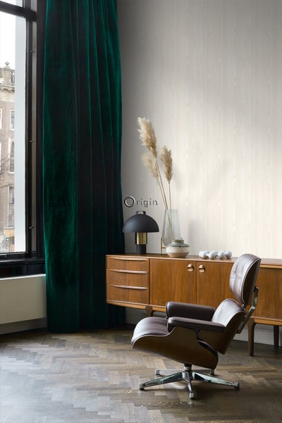 Wohnzimmer mit braunem Ledersessel, Holzkommode, schwarzer Lampe, grünen Vorhängen und hellem Holzboden.