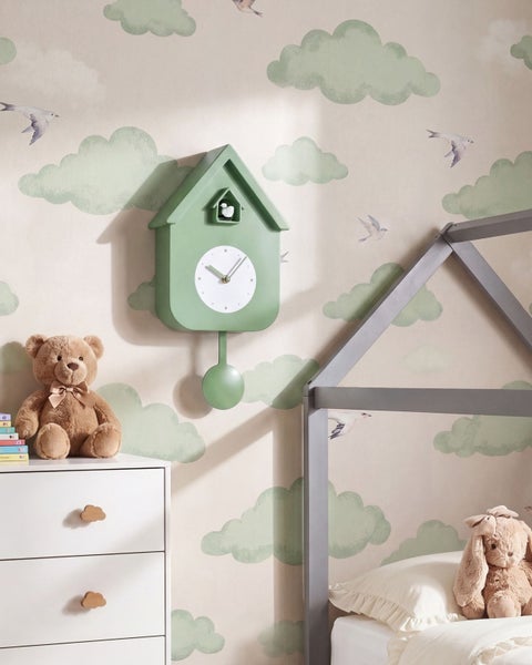 Wanduhr im Kuckucksuhr Design in Hausform an einer Kindertapete mit Wolkenmuster in einem Kinderzimmer mit Kuscheltieren und Hausbett