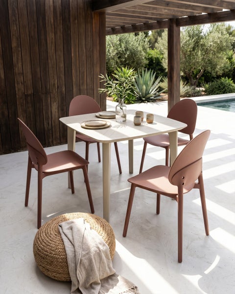 Moderner quadratischer Gartentisch mit vier terracottafarbenen Stühlen auf einer hellen Terrasse mit Pool und mediterranen Pflanzen.