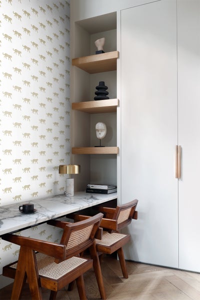 Helles Arbeitszimmer mit Schreibtisch, Stühlen, Regalen und Tapete mit Tiermotiv