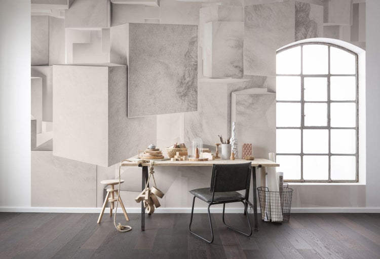 Arbeitszimmer mit Schreibtisch, Stuhl, Hocker und geometrischer Tapete.