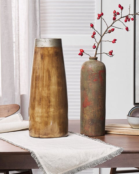 Dekorative Vasen auf einem Tisch mit Tischläufer und Hagebuttenzweig