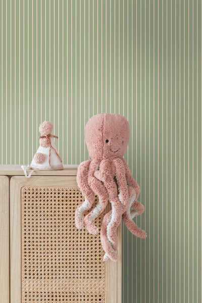 Vlies-Tapete mit vertikalem Streifenmuster in einem Kinderzimmer mit Holzkommode und Stofftier-Oktopus.