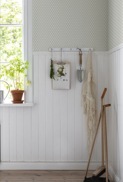 Heller Raum mit Holzvertäfelung, Fenster, Pflanze, Dekoration und Gartengeräten.