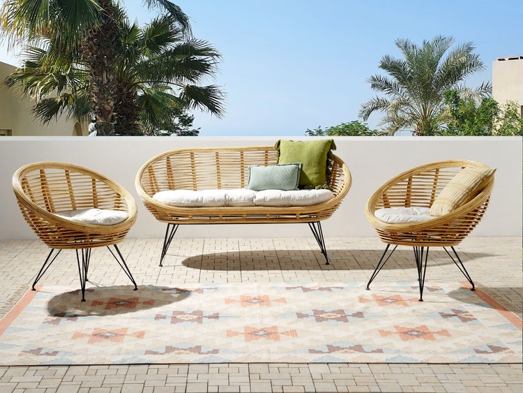 Gartenmöbel-Set mit Rattansofa, Rattansesseln und Teppich auf einer Terrasse